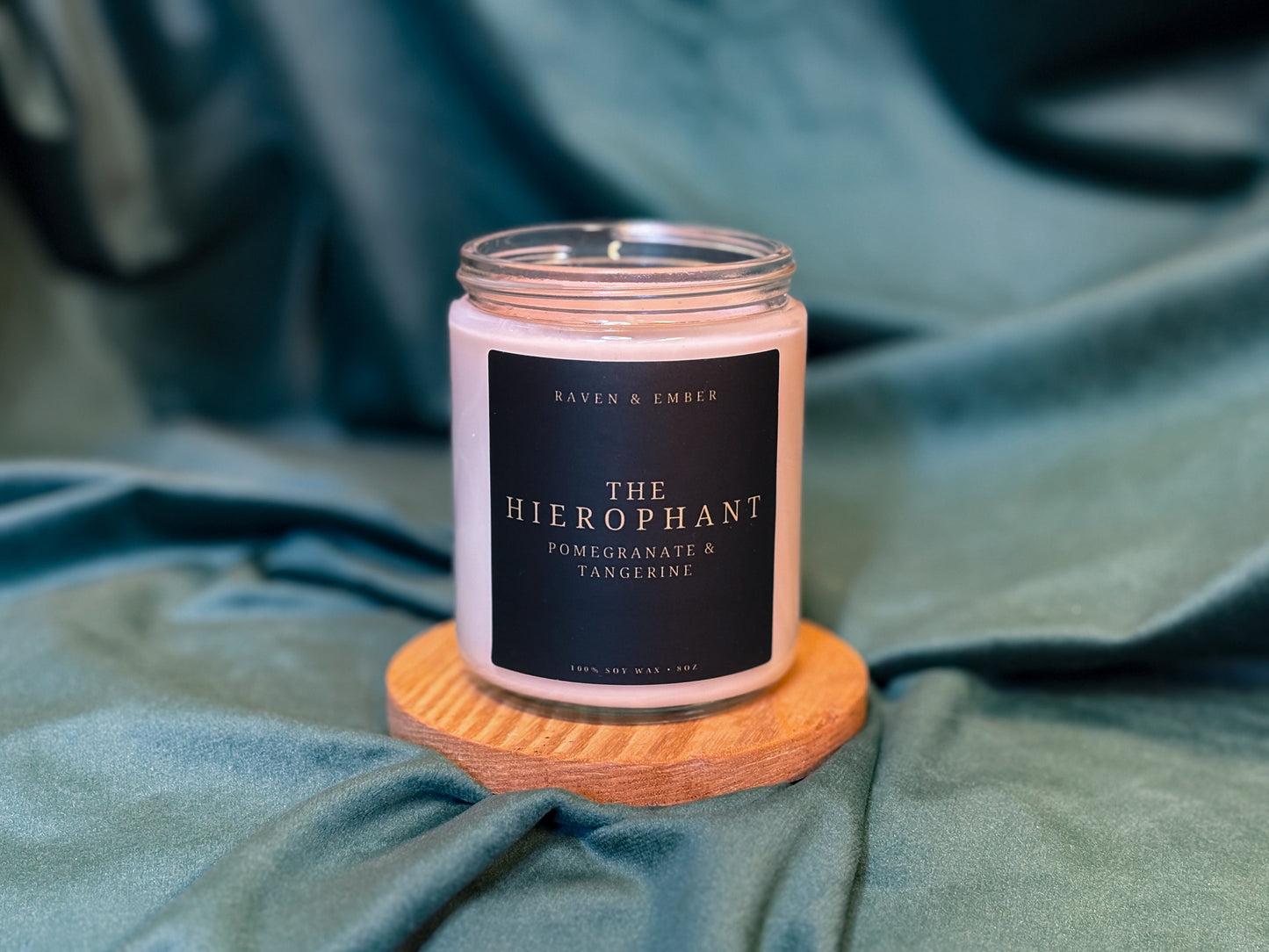 Candle labeled 'The Hierophant' on a wooden coaster with a blue fabric background